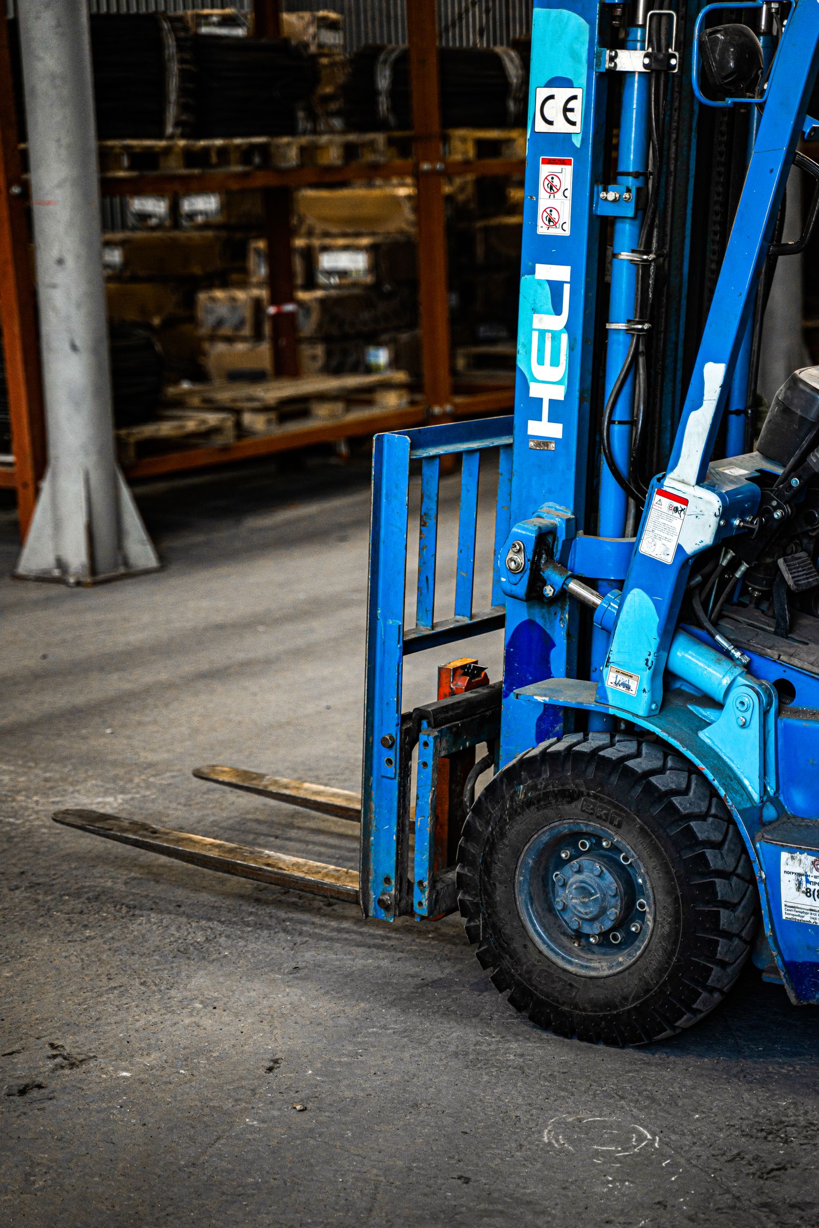 Xe nâng màu xanh trong nhà kho công nghiệp gần kệ hàng