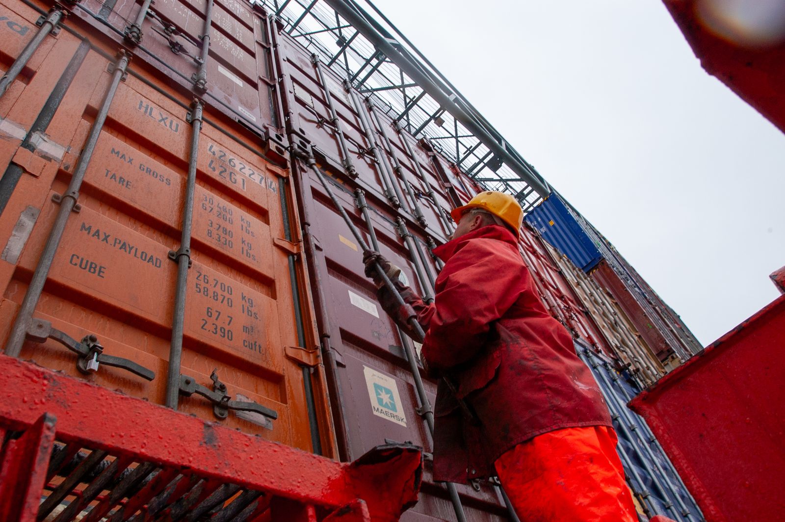 Công nhân cảng cố định container hàng hóa dưới trời mưa