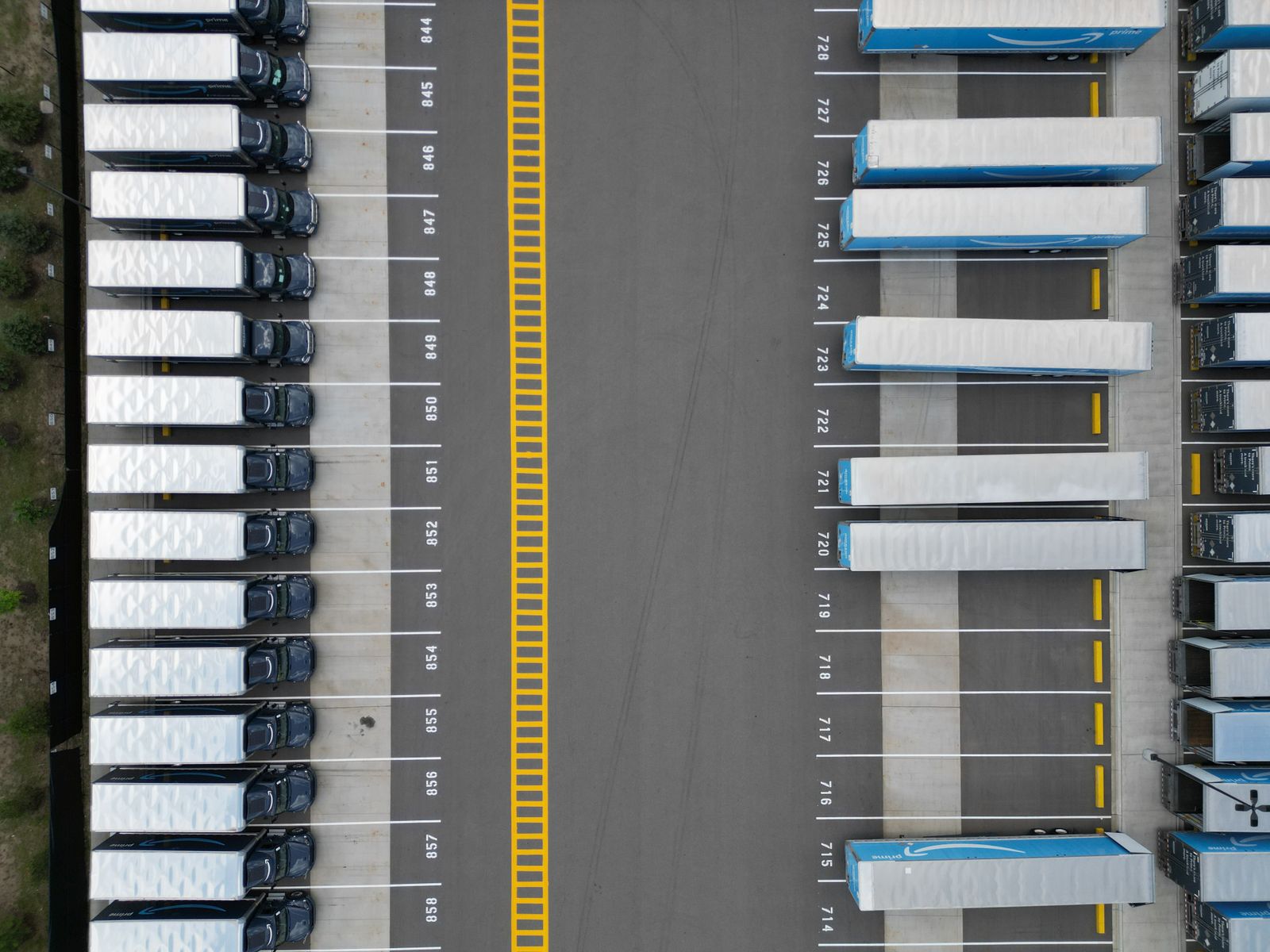 Đội xe tải xếp hàng ngay ngắn tại bãi đỗ logistics nhìn từ trên cao